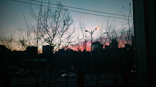 Silhouette of city against sky at sunset