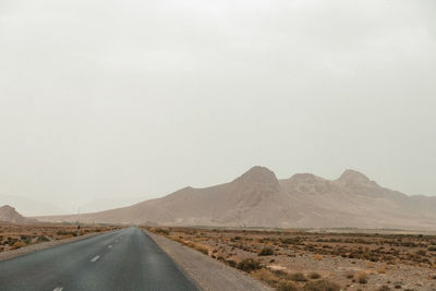 Road by mountains against clear sky