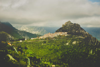 Scenic view of town in rocky mountains against cloudy sky