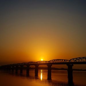 Bridge over river against sky during sunset