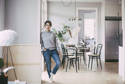 Portrait of woman standing holding laptop at home