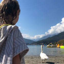 Full length of girl on beach with swan against sky