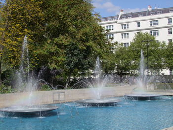 Water splashing in fountain against sky in city