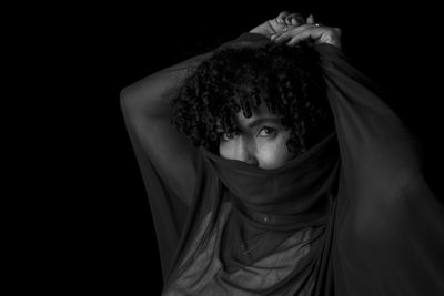 Close-up black and white portrait of woman with transparent cloth on her face 