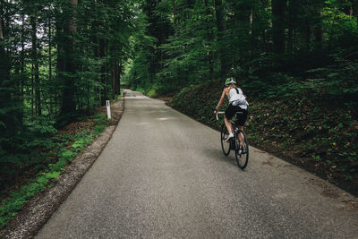 Rear view of man riding bicycle on road