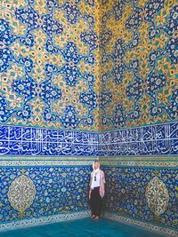 Woman standing against blue patterned wall