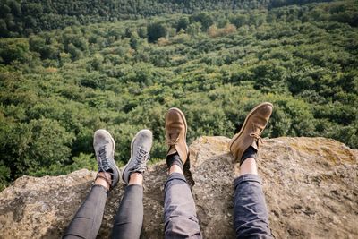 Low section of people on cliff against forest