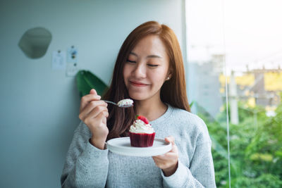 A beautiful asian woman enjoyed eating red velvet cup cake