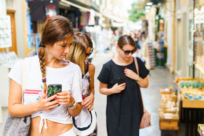 Friends holding mobile phones standing at market