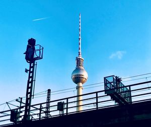 Low angle view of bridge by fernsehturm against blue sky