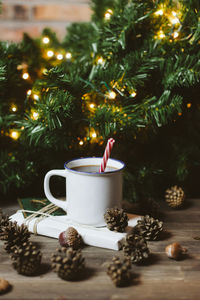 Close-up of drink by christmas tree on floor