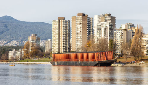 Buildings by river against sky in city