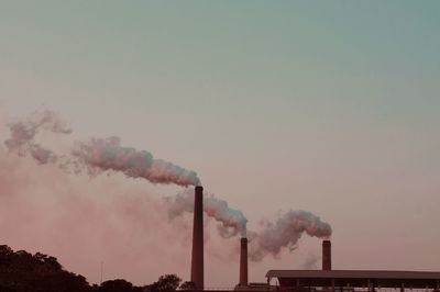 Smoke emitting from factory against clear sky