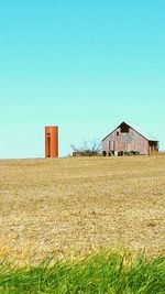 Houses on field against clear blue sky