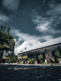 Empty road by buildings against sky