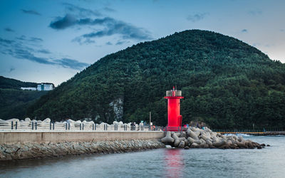 Lighthouse by river against sky