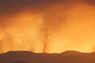 Silhouette of mountain against orange sky