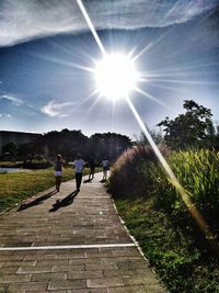 People on sunny day against sky