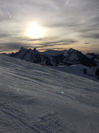 Scenic view of snow covered mountains against sky at sunset