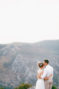 Couple standing on mountain against sky