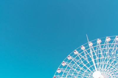 Low angle view of ferris wheel against clear blue sky