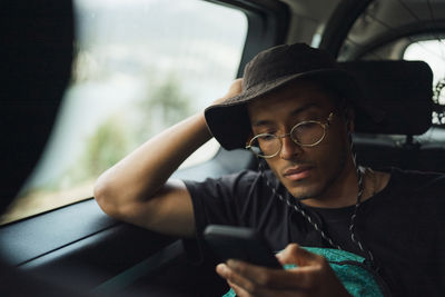 Man leaning on window and using smart phone while sitting in van