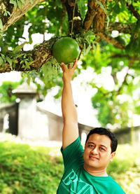 Portrait of boy holding fruit on tree