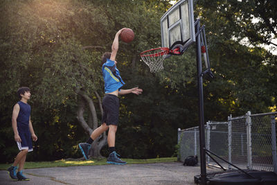 Players playing basketball at court by trees