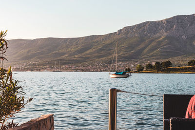 Sailboat sailing on sea against mountains