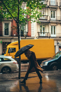 Woman walking on the street in the rain with umbrella