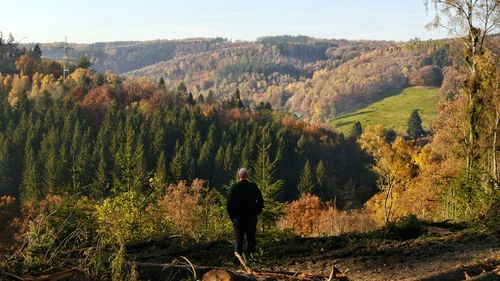 Rear view of man standing on field against sky