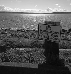 Close-up of signboard by sea against sky