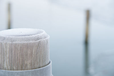 Close-up of wooden post against white wall