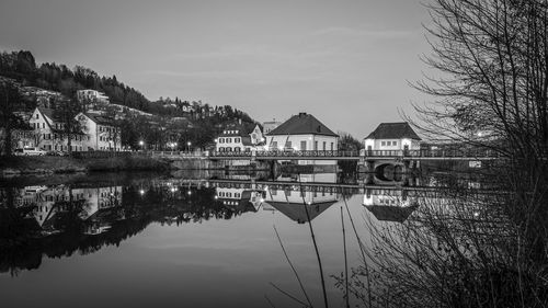 Reflection of building and trees in lake against sky