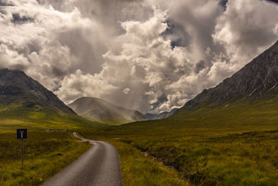 Road leading towards mountains against sky