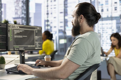 Side view of man using laptop at office