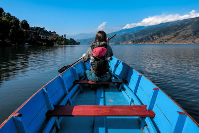 Rear view of woman sitting on boat against sky