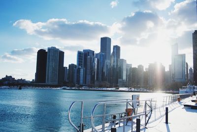 Sea by cityscape against sky