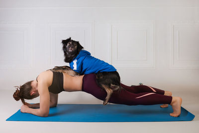Sport with a dog. attractive girl working out on the blue fitness mat with her dog. 