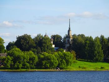 Scenic view of river by trees and building against sky