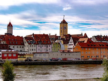 Buildings by river against sky