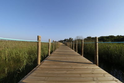 Pier over sea against clear blue sky