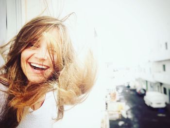 Portrait of smiling young woman with tousled hair standing in balcony