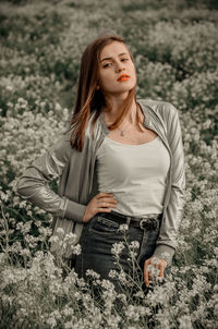 Portrait of young woman standing by plants