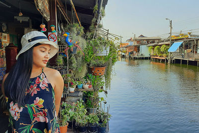 Woman standing by plants against canal