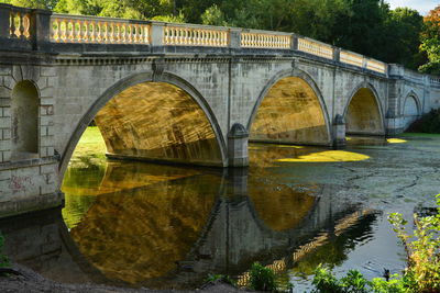 Arch bridge over river against sky