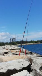 Sailboat on rock by sea against blue sky