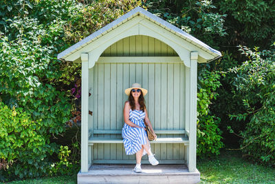 Portrait of woman sitting in small house against trees