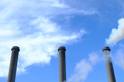 Low angle view of smoke emitting from chimney against sky