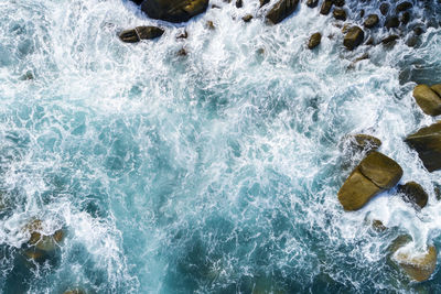 High angle view of waves splashing on rocks